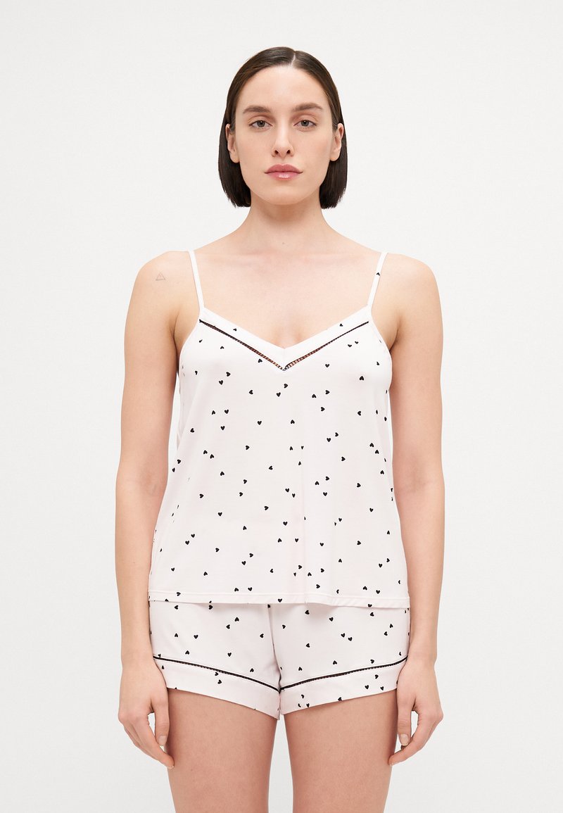 Svijetloružasti pidžama set s crnim printom srca, koji se sastoji od bezrukavog topa s V-izrezom i odgovarajućih kratkih hlača s kontrastnim obrubom.