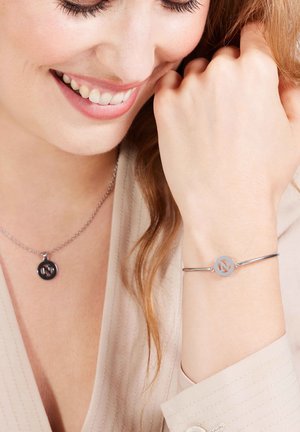 Ensemble de bijoux en argent comprenant un pendentif avec un charme noir circulaire et un bracelet avec un accent circulaire en argent assorti.