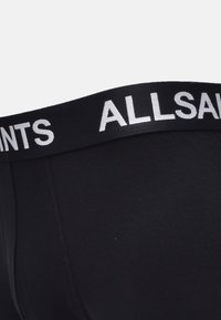 Boxer-briefs noirs avec une ceinture texturée arborant "ALLSAINTS" en lettres blanches contrastées. Tissu doux avec un ajustement serré.
