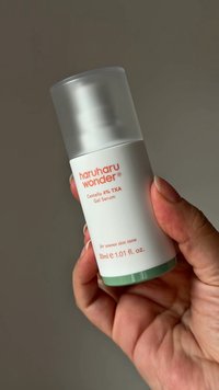 Bottiglia cilindrica bianca con coperchio satinato. Etichetta con testo color pesca che recita "haruharu wonder" e "Centella 4% TXA Gel Serum." Base verde.