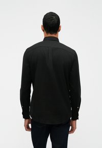 Čierna košeľa s dlhým rukávom a rovnou spodnou časťou, s gombíkovými manžetami, s hladkou textúrou a klasickým golierom.