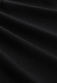 Tissu noir à texture lisse et mate, présentant des plis doux et fluides. La surface est uniforme sans motifs ni matériel visible.