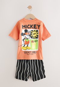 Orange cotton t-shirt with a Mickey Mouse graphic and text; paired with black shorts featuring white vertical stripes.
