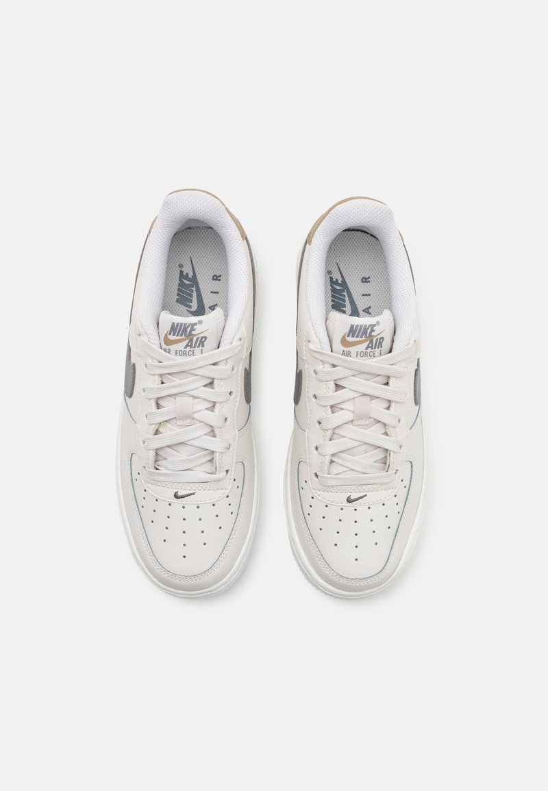 Le sneakers Nike Air Force 1 presentano una tomaia in pelle grigio chiaro, lacci bianchi, dettagli perforati e un logo swoosh grigio scuro.