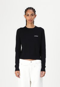 Sort cropped sweater med lange ærmer og rund udskæring, med hvidt broderet logo "2NDDAY" på venstre bryst. Glat tekstur.