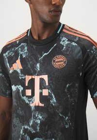 Crni sportski dres s mramornim uzorkom u nijansama tirkizne. Istaknuti detalji uključuju narančaste akcentne boje, logo FC Bayern München i Adidas branding.