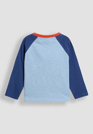 Garšām piedurknēm krekls ar gaiši zilu ķermeni, tumši ziliem raglāna piedurknēm un sarkanu apkakli. Mīksta kokvilnas auduma ar minimāliem dekoriem.