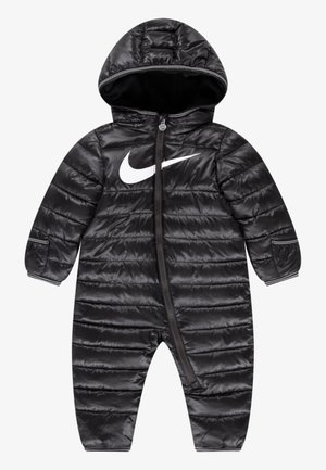 Combinaison de neige matelassée noire pour bébé avec capuche, fermeture éclair intégrale à l’avant et grand logo blanc Nike Swoosh sur la poitrine.