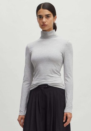 Grijze lange mouwen coltrui met een slim fit en zachte textuur, gecombineerd met zwart hooggeprofileerd geplooid broek, met knoopdetail zichtbaar.