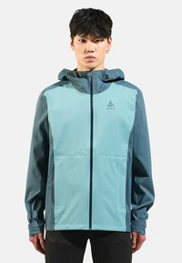 Men's lightweight jacket in teal and dark blue, featuring a zip front, hood, and contrasting color panels. Made from water-resistant material.