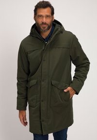 Donkergroen parka jack met een capuchon, voorknopen, twee grote zijzakken en een zachte textuur. Draag ik over denim jeans.