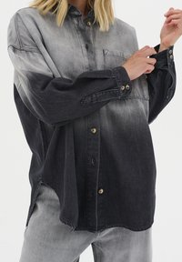 Jeanshemd mit Farbverlauf von hellgrau zu schwarz. Ausgestattet mit durchgehendem Knopfverschluss, Brusttasche und gekrempelten langen Ärmeln. Strukturierter Stoff.
