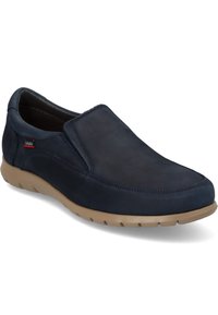 Zapato slip-on de cuero en color navy con textura suave, suela de goma color marrón acolchada y detalles de costura mínimos. El logotipo lateral está sutilmente destacado.