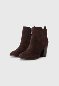 Stivali alla caviglia in suede marrone con tacco spesso, punta arrotondata, chiusura lampo laterale e design minimalista.