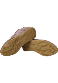 Zapatillas deportivas de ante con un diseño de perfil bajo en un marrón suave, que cuentan con una suela de goma texturizada con un patrón en zigzag y una marca grabada.