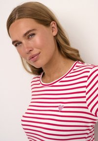 Rood-wit gestreept t-shirt van zacht katoen, met een klein geborduurd roze hartje op de linker borst en een ronde halslijn.