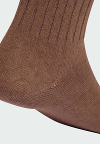 Brązowa bawełniana skarpeta o prążkowanej fakturze, dopasowanym kształcie i wzmocnionym obcasie. Bezszwowy design palców, gładkie wykończenie i jednolity kolor.
