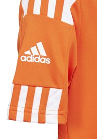Camiseta atlética naranja con acentos de tres rayas blancas en las mangas, hecha de una tela suave con un logo de Adidas bordado en blanco.