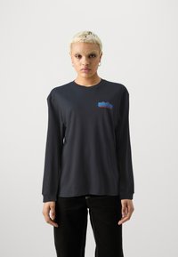 Langærmet sort t-shirt med rund halsudskæring og blødt bomuldsstof. Har et logo i blå og rød på venstre bryst.