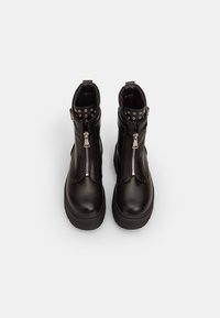 Stivali alla caviglia in pelle nera con zip argentate e dettagli con borchie sul colletto. Suola spessa e texture liscia, caratterizzati da un design elegante.