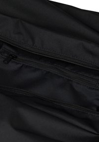 Bolsa de tela negra con una textura suave y duradera. Cuenta con un cierre superior y un compartimento con cremallera más pequeño en el interior para la organización.