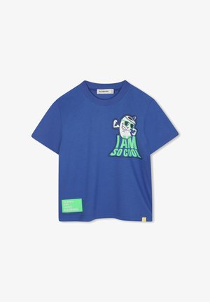 T-shirt en coton bleu avec un grand graphisme d'un personnage de dessin animé musclé et le texte "JE SUIS TELLEMENT COOL." Comprend une étiquette verte avec la mention "LE MONDE EST MON PARC DE LOISIRS PRÉFÉRÉ."