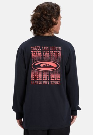 Camiseta negra de manga larga con un diseño gráfico rosa en la parte posterior que incluye el texto "Sabe a Cielo" en una fuente distorsionada y ondulada.