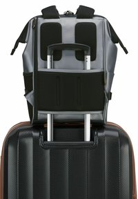 Valigia a mano nera con superficie texturizzata, sovrastata da uno zaino grigio con accenti in rete e manico retrattile.