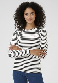 Langarm shirt met zwarte en witte strepen, met een klein roze hartje op de borst. Zachte stof met een aansluitend model.