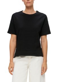 Zwart T-shirt met korte mouwen, horizontale textuurstrepen, ronde halslijn, een comfortabele pasvorm en zachte stof. Gecombineerd met lichtgekleurde broeken.
