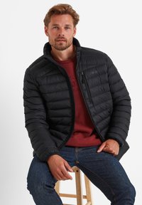 Black puffer jacket with horizontal quilting, standing collar, and zippered pockets. Worn over a maroon sweater, paired with blue jeans.