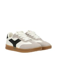 Zapatillas de deporte en gris claro y blanco, hechas de ante y materiales sintéticos. Presenta un acento de malla negra y una suela de goma color caramelo. Diseño con cordones.