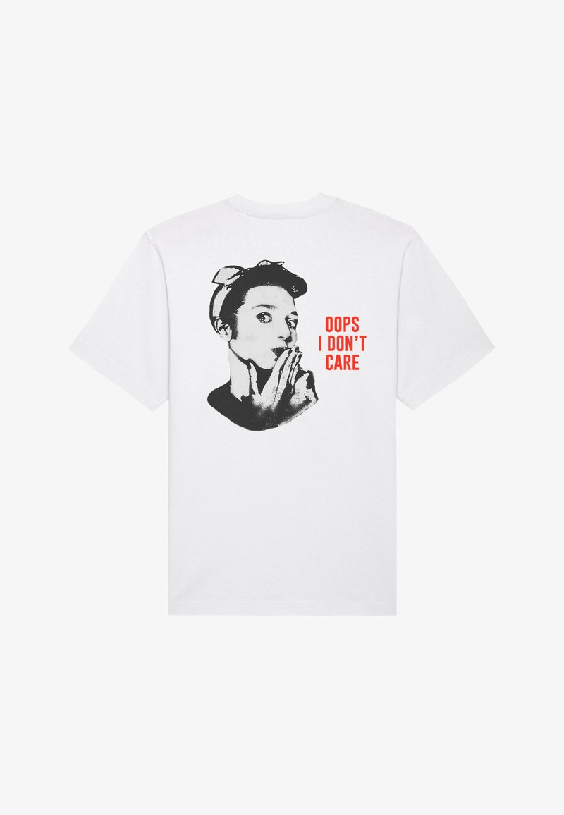 T-shirt en coton blanc avec un graphique noir représentant une personne portant un bandeau et le texte "OUPS, JE ME FOUS DE TOUT" en rouge gras, situé au dos.