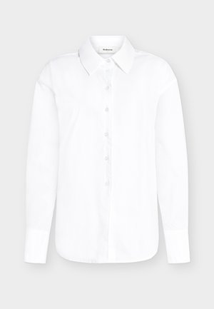 Cămașă albă cu mâneci lungi, cu nasturi, guler ascuțit și manșete cu nasturi, pe un fundal gri deschis.