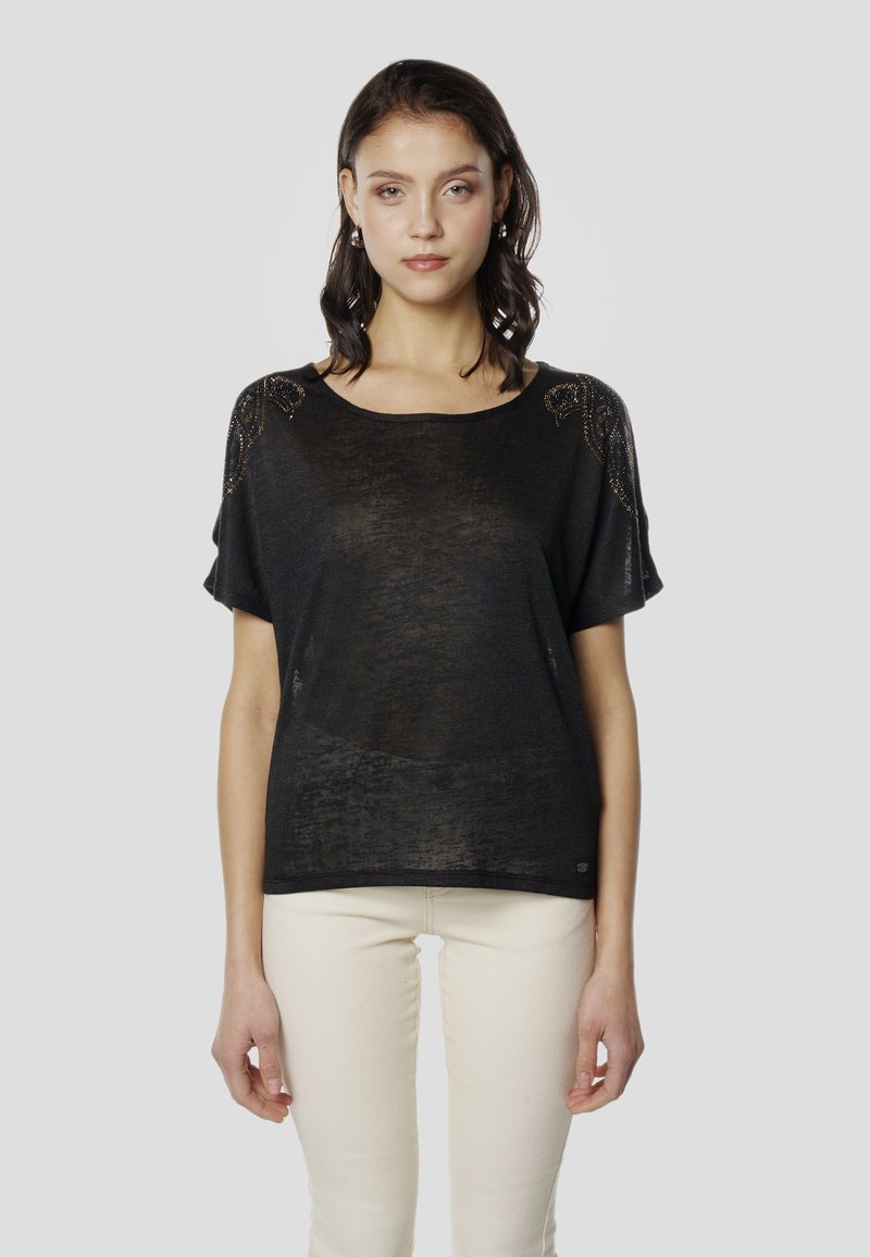 Fekete rövid ujjú pulóver laza szabással, díszített vállrészletekkel és lekerekített nyakkivágással. Könnyű, texturált anyagból.