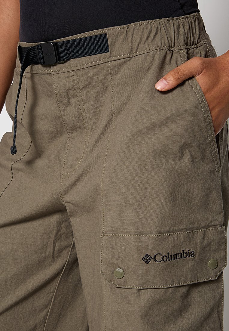 Beżowe spodnie cargo z elastycznym pasem, regulowanym czarnym paskiem, bocznymi kieszeniami i logotypem Columbia na prawym nogawce. Lekka faktura materiału.