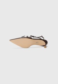 Scarpa con tacco alto in pelle verniciata marrone, punta affusolata, sottile cinturino alla caviglia e suola beige texture. Presenta un piccolo tacco posteriore.
