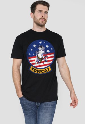 Schwarzes Baumwoll-T-Shirt mit einem Grafikdruck eines Cartoon-Katers auf einem blau-rot gestreiften Hintergrund mit Sternen, beschriftet "TOMCAT" in Gelb.