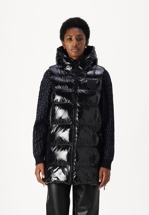 Gilet nero imbottito con finitura lucida, cappuccio e maniche testurizzate con accenti a fantasia. Chiusura con zip e dettaglio del logo sul petto.
