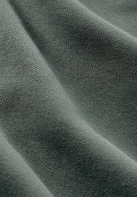 Měkká, žebrovaná látka v tlumené zelené barvě, s jemnou texturou a hladkým povrchem, ideální pro oděvy nebo čalounění.