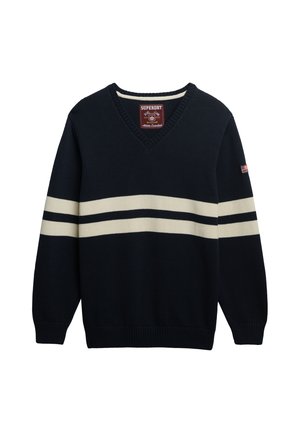 Marineblå v-hals sweater med cremefarvede vandrette striber og ribkanter. Har mærkelabel på halsen og en lille amerikansk flagdetalje på ærmet.