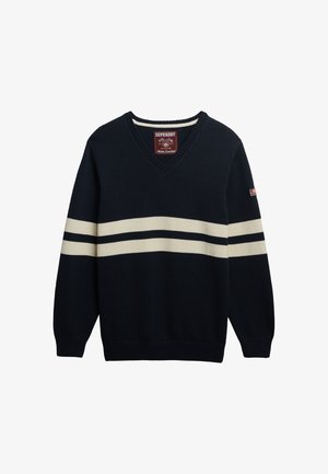 Marineblå v-hals sweater med cremefarvede vandrette striber og ribkanter. Har mærkelabel på halsen og en lille amerikansk flagdetalje på ærmet.