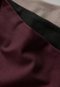Drei überlappende Stoffmuster: bordeauxrot, schwarz und hellbeige. Texturierte Materialien mit glatter Oberfläche. Saubere Kanten und Nähte sichtbar.