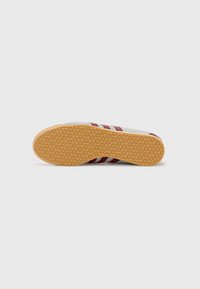 Hvide sneakers med røde striber, der har en struktureret gummisål. Overdelen er glat og viser et klassisk low-top design.