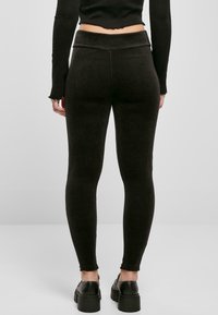 Leggings noirs côtelés avec une taille haute, texture lisse et design ajusté, associés à des chaussures noires épaisses.