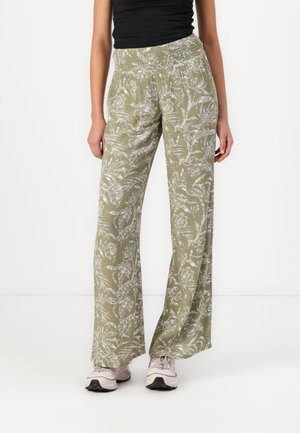 Light green wide-leg pants made of textured fabric with white floral patterns, featuring an elastic waistband. Paired with light pink sneakers.
