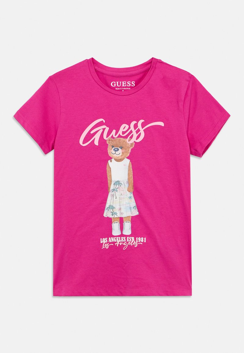 Ροζ μπλουζάκι με εικόνα αρκούδας σε λευκό φόρεμα με μοτίβα φοίνικα και το κείμενο "Guess" και "Los Angeles Est. 1981".