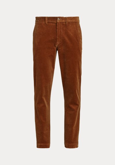 Bruine slim-fit corduroy broek met riemlussen, een knoopsluiting en twee zijzakken, getoond op een witte achtergrond.