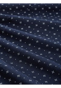 Tessuto blu marina con piccoli motivi floreali bianchi, texture morbida, drappeggiato in pieghe, che mostra il suo design e i dettagli.