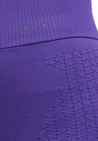Paarse sportleggings met een geribbelde textuur en geweven patronen. Heeft een logo "FALKE" in een contrasterende kleur op de taille.